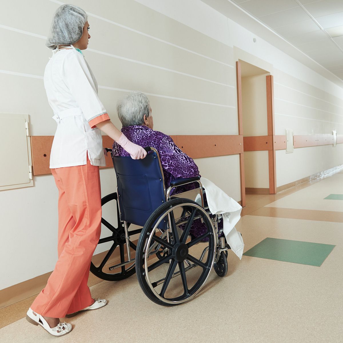 Стационарное обслуживание инвалидов и престарелых. Кресло каталка для перемещения пациента. Транспортировка пациента на кресле каталке. Инвалидная коляска в больнице.